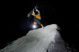 snowboarder riding down the snowy mountain slope at the dark night
