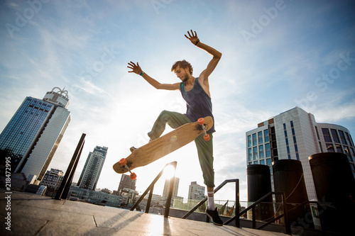 Young skateboarder jumping on board against city buildings