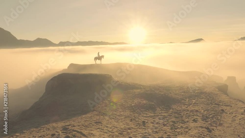 Horseman standing at fog covered mountain cliff waiting for tourist at sunrise, timelapse clip, Bromo