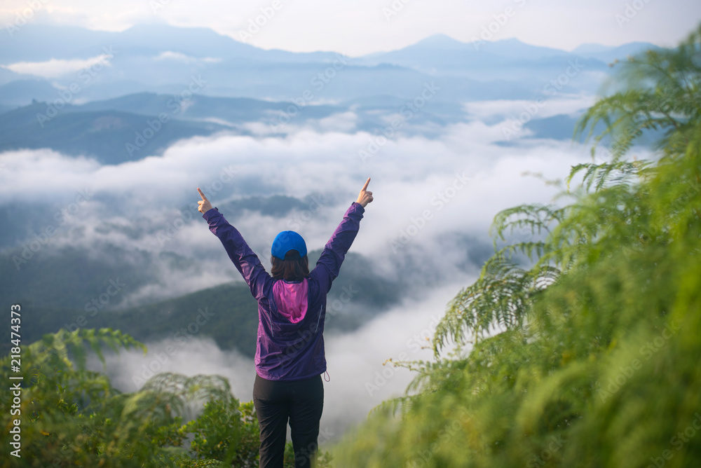 Tourist woman standing on peak of mountains and enjoy view with beautiful mist and sunrise from her success at Gunungsilepat mountains, Yala province south of Thailand. Tourist woman standing on peak of mountains and enjoy view with beautiful mist and sunrise from her success at Gunungsilepat mountains, Yala province south of Thailand.
