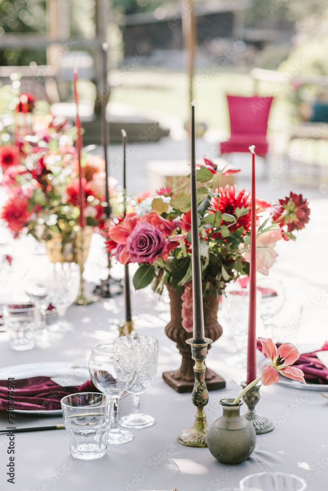 Rustic banquet, candels, glasses, red and pink flowers. Elegance and light is around