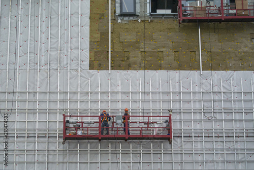 Construction of a hotel. Workers on suspended scaffolding 