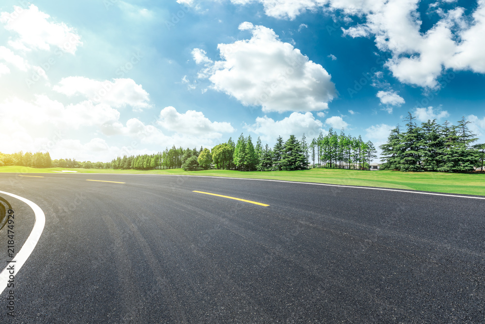 Fototapeta premium Empty asphalt road and green forest landscape under the blue sky