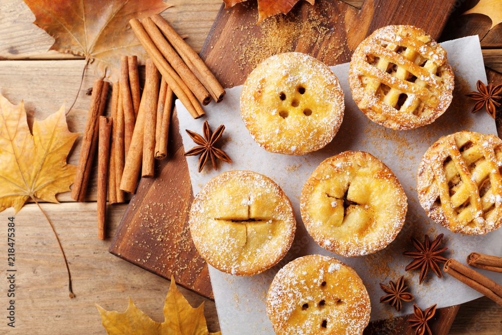 Set of different mini apple pies decorated sugar powder and cinnamon on wooden board top view. Autumn pastry dessert. Set of different mini apple pies decorated sugar powder and cinnamon on wooden board top view. Autumn pastry dessert.