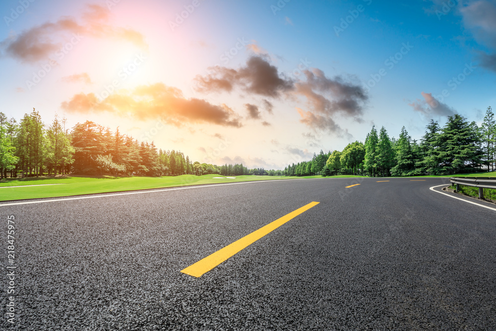 Fototapeta premium Empty asphalt road and green forest landscape at sunrise