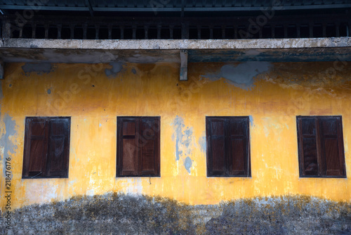 Wooden windows on old yellow wall cracked from the wall, retro and Thai traditional and classic style outside of house.