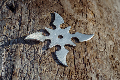 Shuriken (throwing star), traditional japanese ninja cold weapon stuck in wooden background