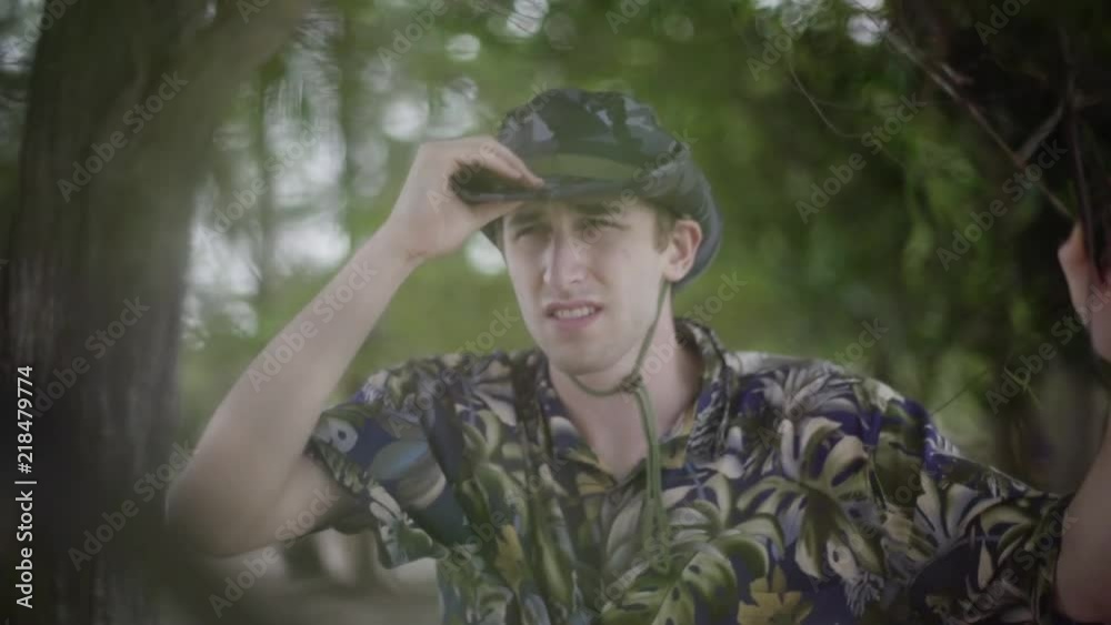 Safari explorer in tropical jungle puts on his hat as he explores environment Safari explorer in tropical jungle puts on his hat as he explores environment
