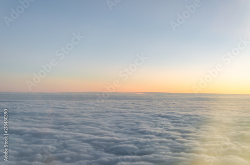Photograph of a landscape from the sky full of clouds in full sunrise with some orange tones.