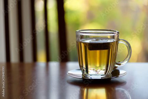 a cup of morning tea on the kitchen table, in the background blurred plants on the balcony