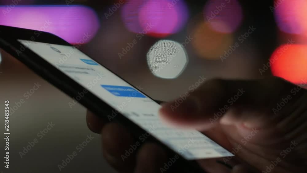 Typing and receiving chat messages on smartphone at night with bokeh color lights in background