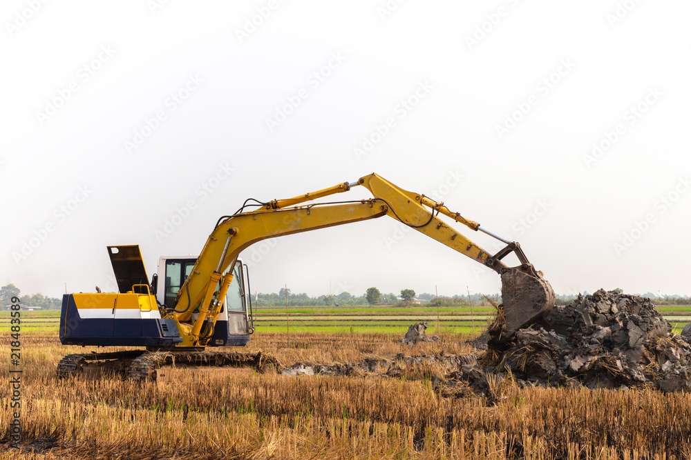 excavator backhoe working in the digging a soil to adjust the postharvest areas in the rice fields. agriculture machinery for modern agriculture industry. excavator backhoe working in the digging a soil to adjust the postharvest areas in the rice fields. agriculture machinery for modern agriculture industry.
