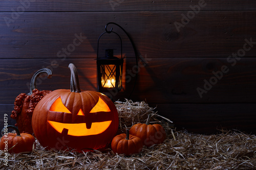 Carved pumpkins or so called jack-o-lanterns in dark barn, Halloween holiday celebration concept