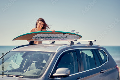 Summer holiday road trip vacation- surfer girl at the beach getting ready for surfing.