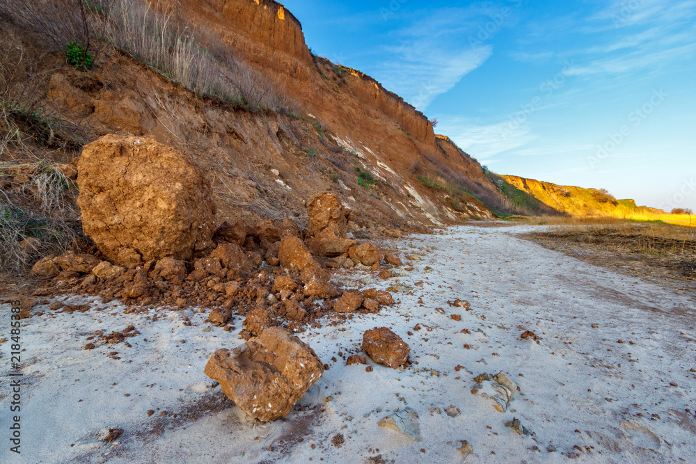 Clay boulder under steep seaside cliff. Erosion process