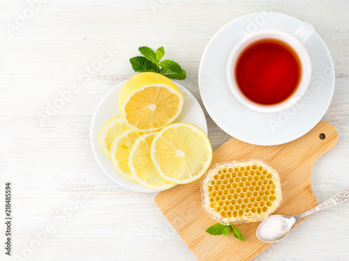 White Cup of tea, honey, honeycomb, lemon on white background. Folk method of treating colds, top view