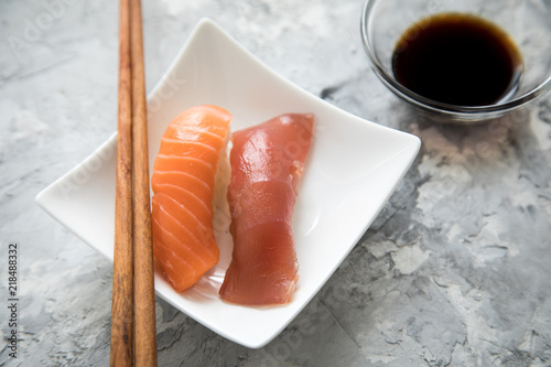 Lachs und Tunfisch Nigiri Sushi mit Sojasauce und Holz Stäbchen auf Porzellan Teller photo