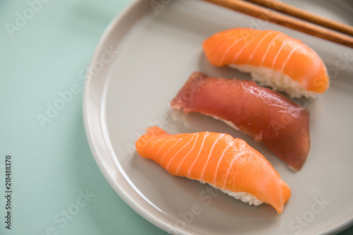 Lachs und Tunfisch Nigiri Sushi mit Holz Stäbchen auf Porzellan Teller
