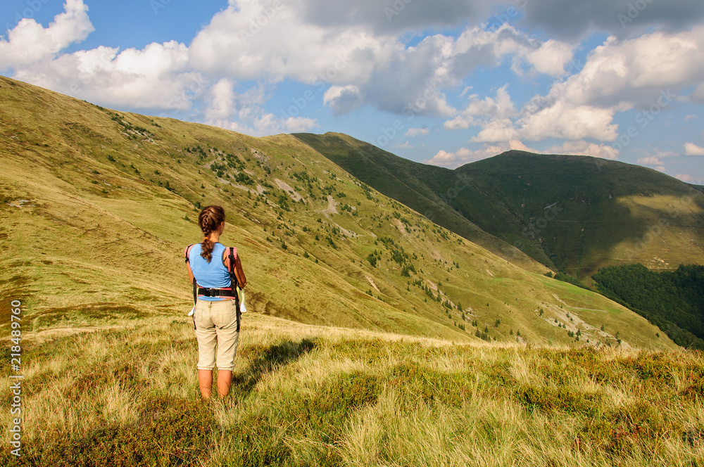 A girl with baby in a sling looks at the mountain range. Ukraine. Carpathian mountains