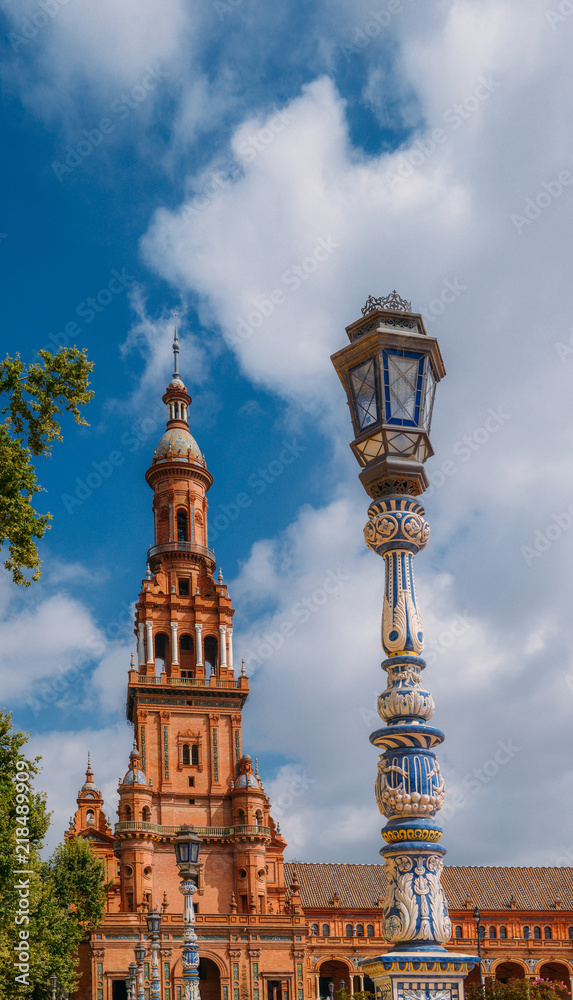 Juxtaposition of blue and white ceramic azulejo tiles against one of the baroque sandstone tower at Plaza de Espana in Seville, Spain