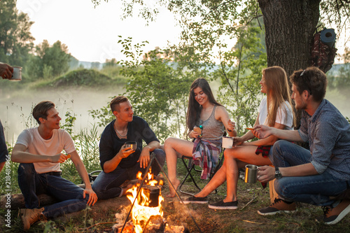 cheerful young people warming near the camp fire. warmth concept. unforgettable moments with best friends photo