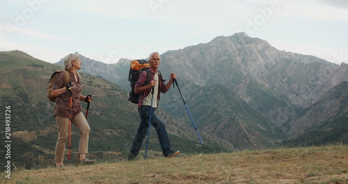 Active senior caucasian couple hiking in mountains with backpacks, enjoying their adventure 4k