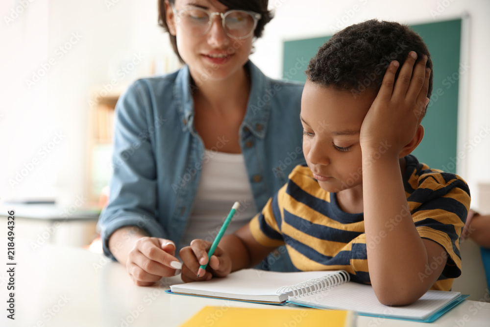 Female teacher helping child with assignment at school Female teacher helping child with assignment at school
