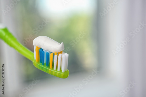 Toothbrush with paste on blurred background, closeup