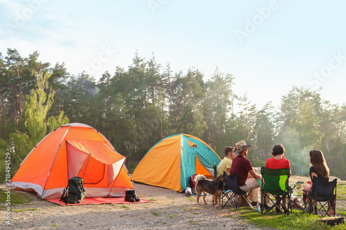 People resting near camping tent in wilderness