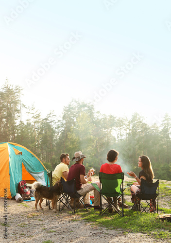 People resting near camping tent in wilderness