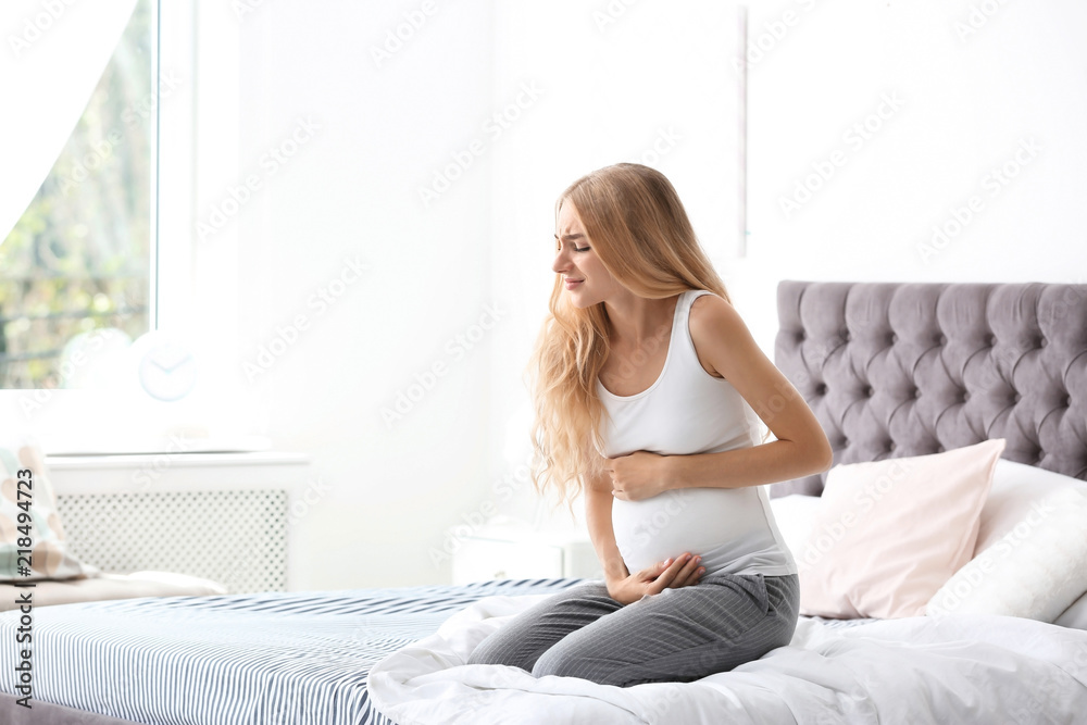 Young pregnant woman suffering from pain in bedroom. Gynecology concept Young pregnant woman suffering from pain in bedroom. Gynecology concept