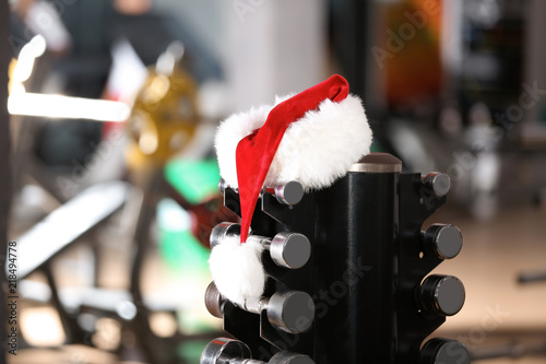 Santa Claus hat on stand with dumbbells in gym