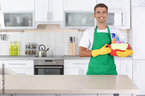 Man with basin and cleaning supplies in kitchen