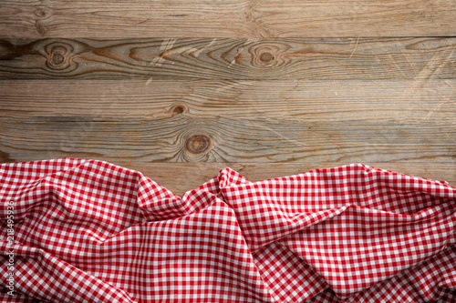Red white checkered picnic tablecloth on wooden background, copy space