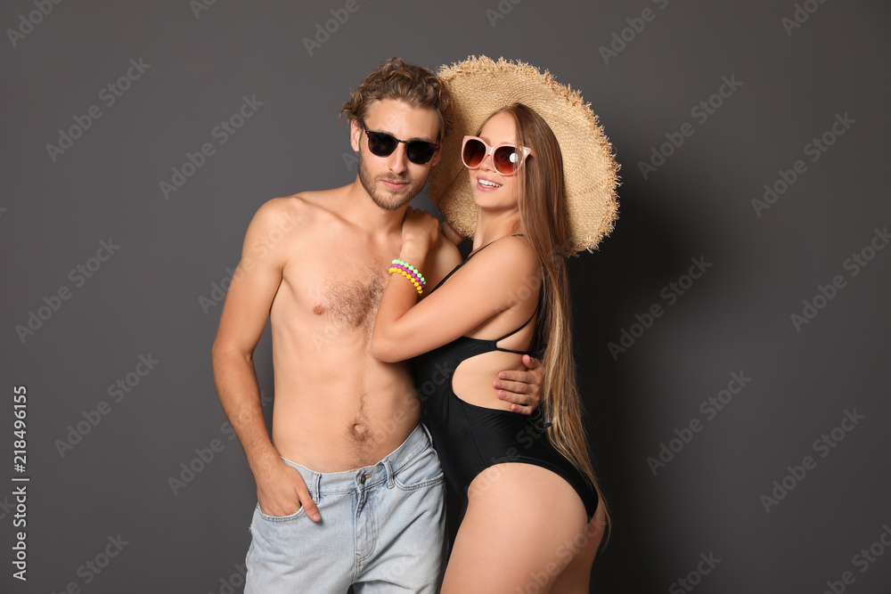 Happy young couple in beachwear on dark background Happy young couple in beachwear on dark background
