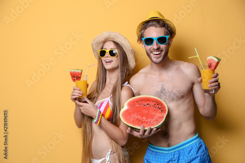 Young couple in beachwear with cocktails on color background