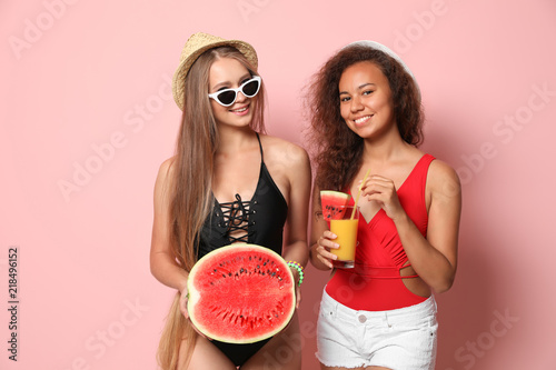 Beautiful young women in beachwear with watermelon on color background