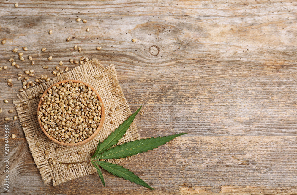 Bowl of hemp seeds and space for text on wooden background, top view - obrazy, fototapety, plakaty 