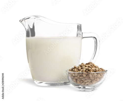 Bowl with hemp seeds and jug of milk on white background