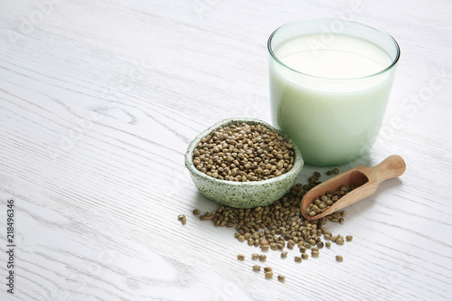 Hemp seeds and glass of milk on wooden background