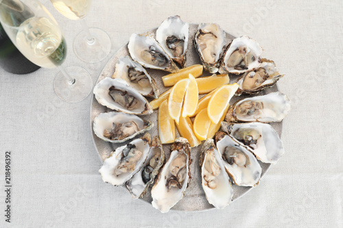 Fresh oysters with cut juicy lemon served on table, top view