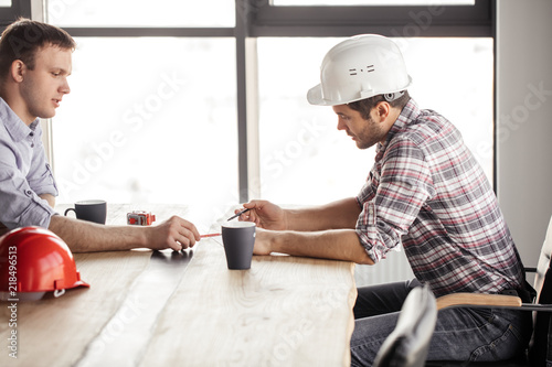 two builders writing a project while resting indoors. side view photo photo
