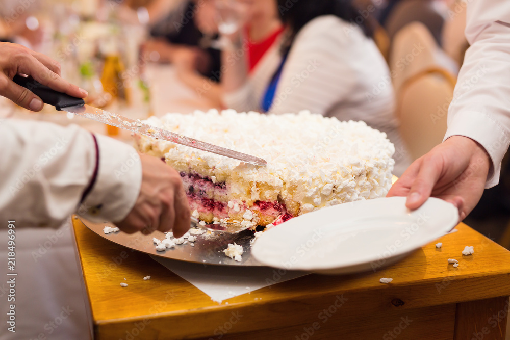Closeup of hands cutting a cake
