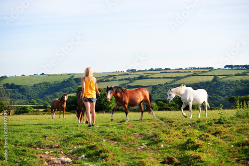 Young woman in a field with horses in landscape © Sy Finch
