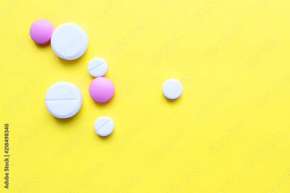 a lot of colorful pills of different shapes on a yellow background. 