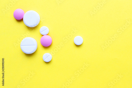 a lot of colorful pills of different shapes on a yellow background. 