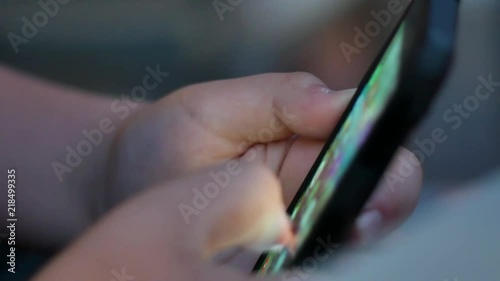 pretty teenage boy looks into the phone playing.
