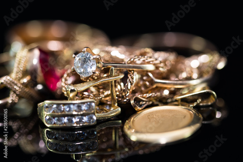 Real gold rings with diamonds, gem, neckless close up macro shot on black background.