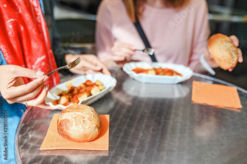 Woman Eating Currywurst with bread in Berlin street food cafe. Local german cuisine concept