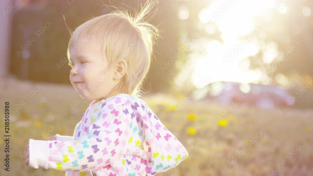 Adorable toddler girl walks through the yard at sunset in autumn Adorable toddler girl walks through the yard at sunset in autumn